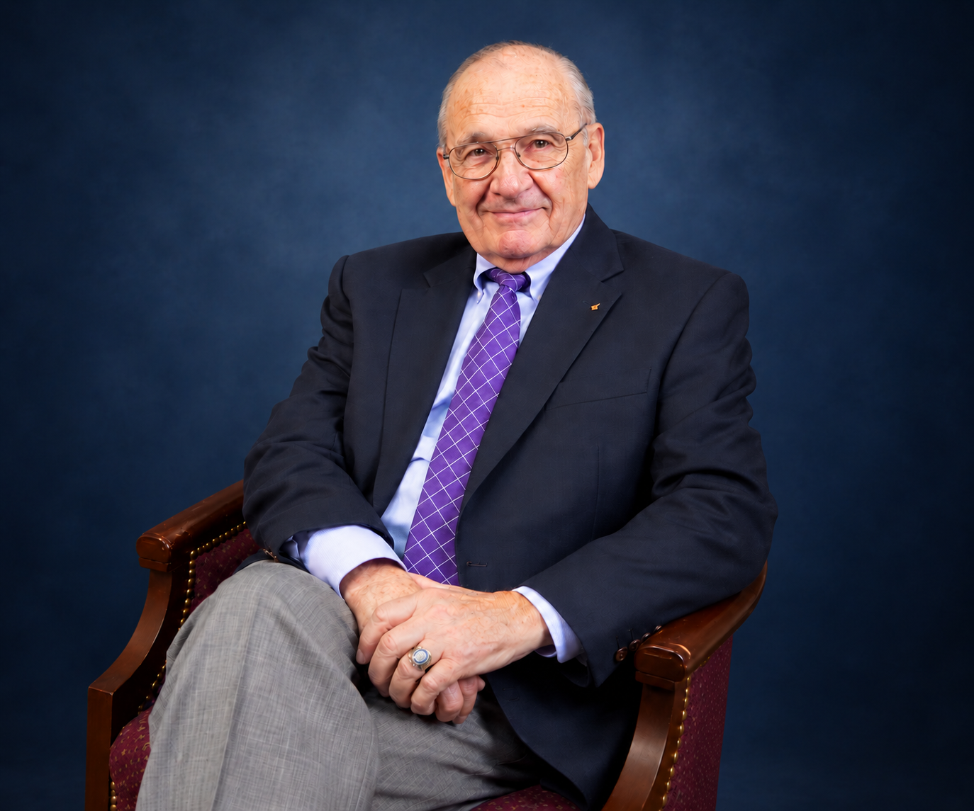 Charles Parrish Professional Portrait Professional portrait of Charles Parrish seated in a chair against a dark blue studio background.